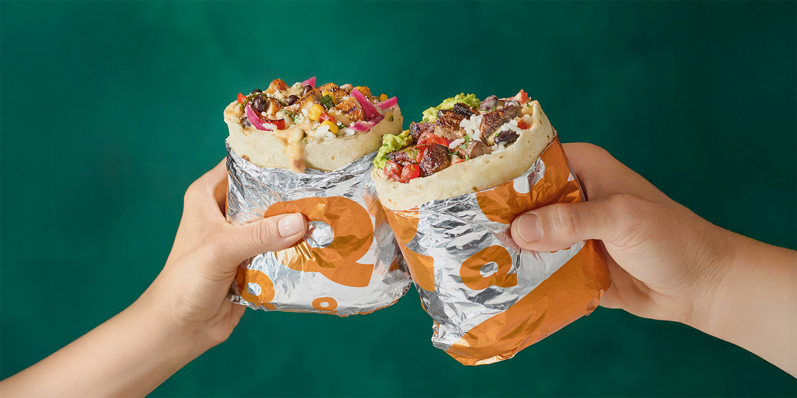 Two QDOBA burritos held up in a celebratory toast, filled with fresh ingredients, promoting QDOBA West Des Moines grand opening