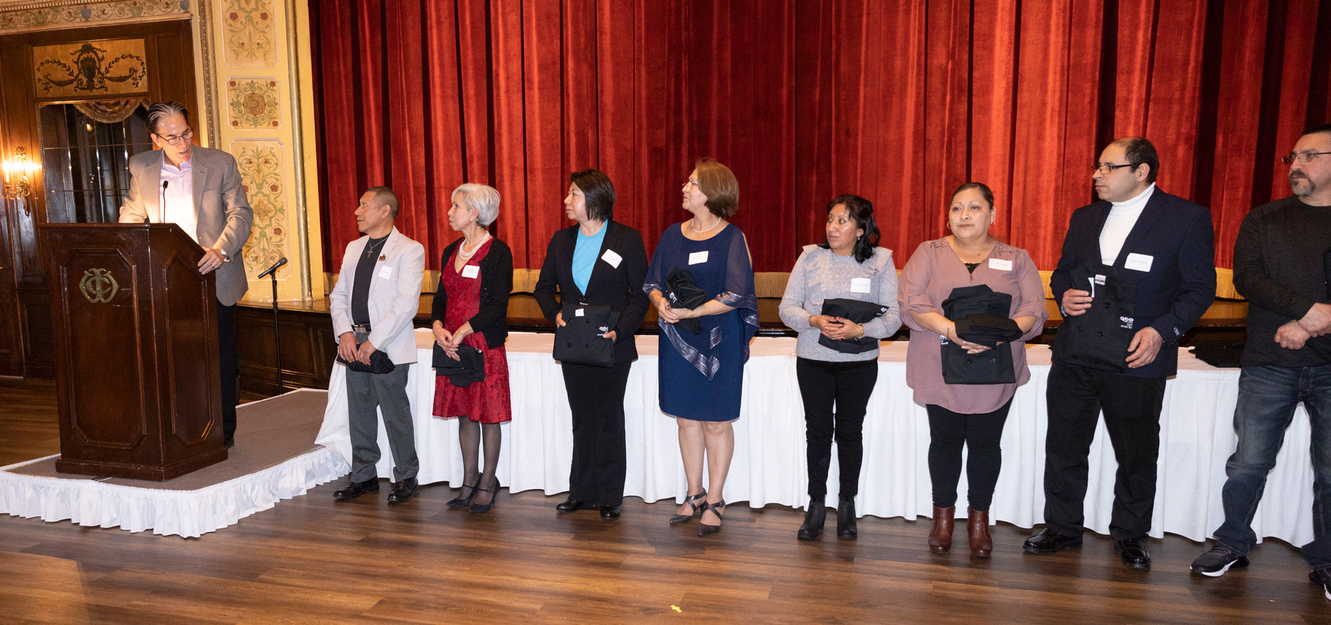 Image: Company leader Ron Stokes stands at a podium, acknowledging and celebrating several team members for their outstanding accomplishments during the Roaring Fork Restaurant Group annual holiday party and awards dinner held at the Wisconsin City Club.